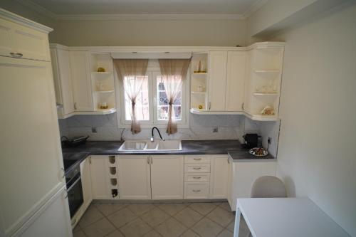 a kitchen with white cabinets and a sink and a window at Bruskos Holiday Deluxe in Kynopiástai