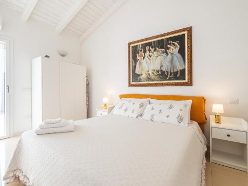 Dormitorio blanco con cama blanca y pintura en la pared en Casa Giovele, en Selargius