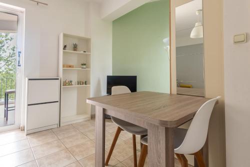 a dining room with a wooden table and white chairs at Elia mini suites 5 in Larisa
