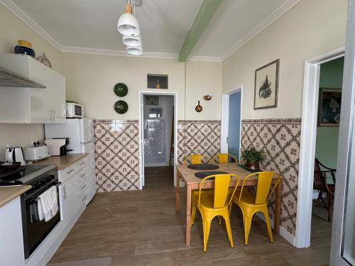 a kitchen and dining room with a table and yellow chairs at Rose's Cottage Foz in Foz do Arelho