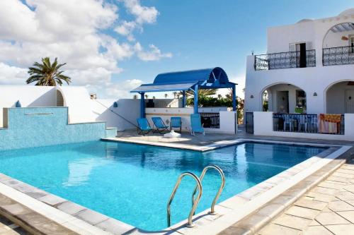 a swimming pool with chairs in front of a house at Spacious villa with private pool in Djerba in Houmt Souk