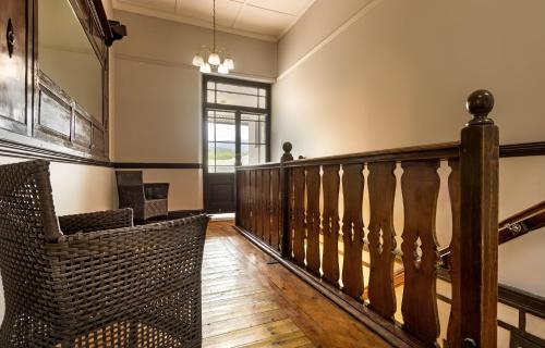 a hallway with a staircase with a chair and a window at Clanwilliam Hotel in Clanwilliam
