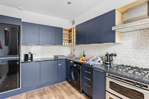 a kitchen with blue cabinets and a washer and dryer at Harbour Heights Plymouth - Centrally located - Parking - Ocean City Retreats in Plymouth