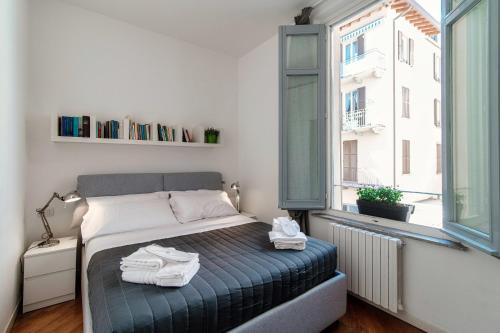a bedroom with a bed and a window with books at Como Luxury Suites - IL DUOMO in Como