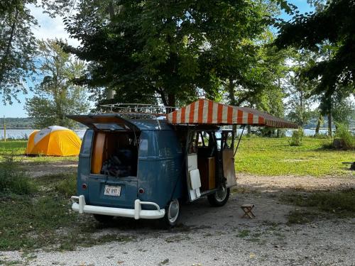 渥太華的住宿－KAYAK STARVED ROCK CAMPGROUND，一辆蓝色面包车停在一个有帐篷的田野里
