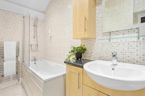a bathroom with a white sink and a bath tub at Harbour Heights Plymouth - Centrally located - Parking - Ocean City Retreats in Plymouth