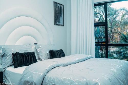 a white bed in a room with a window at Casa de Amor - Stylish Apartment in Rosebank in Johannesburg