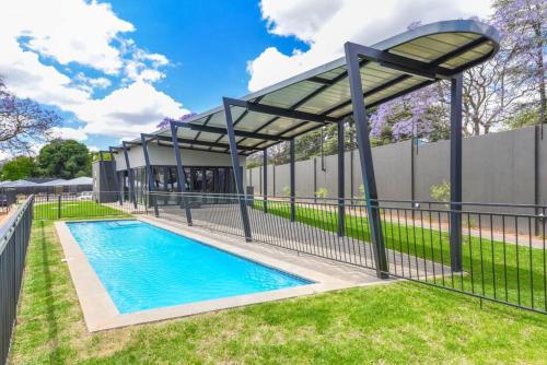 a swimming pool with a pavilion next to a fence at Casa de Amor - Stylish Apartment in Rosebank in Johannesburg
