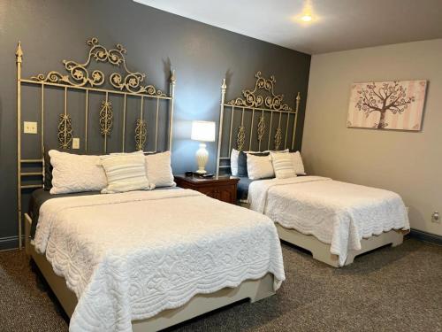 a bedroom with two beds with white sheets and golditures at The Bank Hotel in Lake Arthur