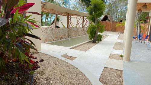 a garden with a swimming pool and a house at Hotel & Eco Cabañas Azul María Bacalar- Gratis Club de playa in Bacalar