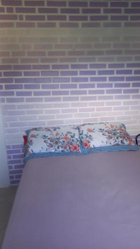 a bed with a pillow on it with a brick wall at Caiowa Floripa guesthouse in Florianópolis