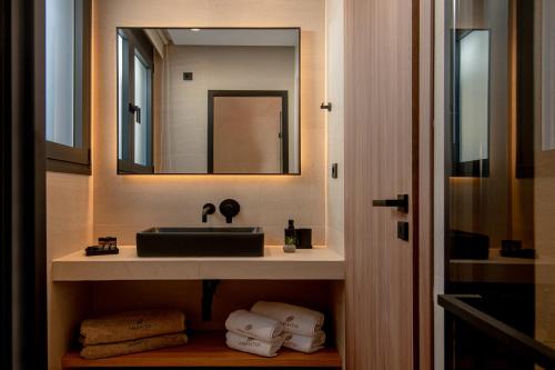 La salle de bains est pourvue d'un lavabo, d'un miroir et de serviettes. dans l'établissement Anantia Luxury Maisonette - Scenic View, à episkopi-heraklion