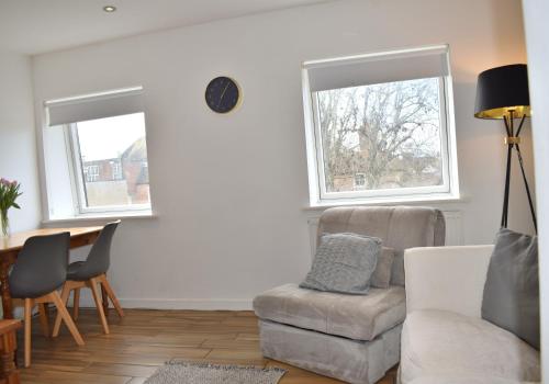 a living room with a couch and a table and two windows at Cathedral View - Chichester City Centre Top Floor Apartment in Chichester