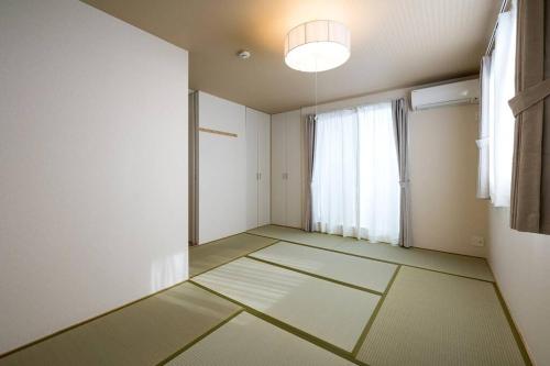 an empty room with a window and mats on the floor at Aile House Ⅰ in Takasaki