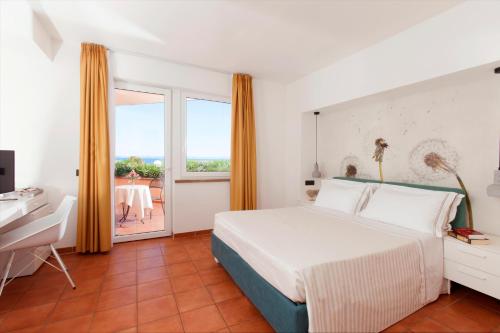 a bedroom with a bed and a desk and a window at Hotel Villa Domizia in Porto Santo Stefano