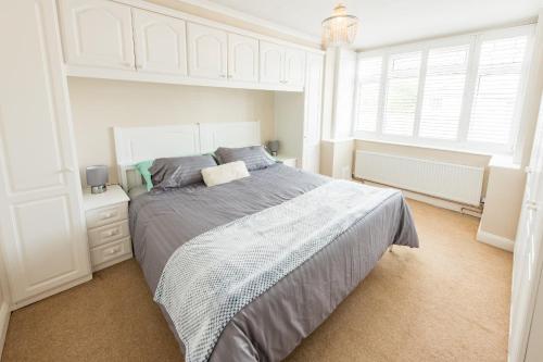 a bedroom with a large bed and two windows at Cosy Family Home in Ruislip in Ruislip