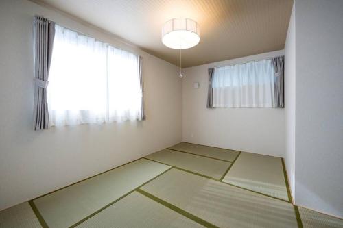 an empty room with a large window and white walls at Aile House Ⅰ in Takasaki