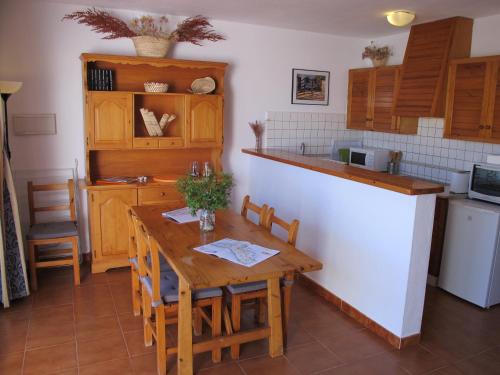 cocina con mesa de madera con sillas y barra en Apartamento junto a Es Clot de Sa Cera a 5 min Ciutadella, en Cala Santandria