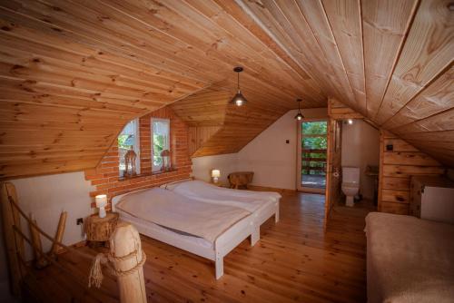 a bedroom with a large bed in a wooden ceiling at Domek Wiejski w Skarlance in Zbiczno