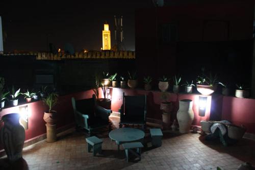 Habitación oscura con mesa, sillas y macetas. en Ryad Meknassia en Meknès