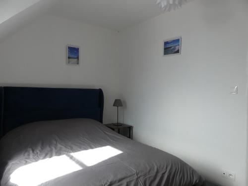 una cama en una habitación con una pared blanca en Comme chez vous, en Le Crotoy