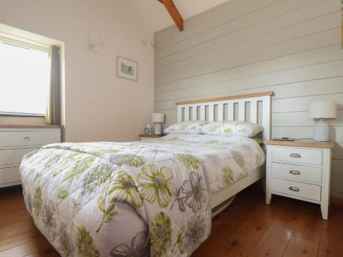 a bedroom with a bed and a night stand and a window at The Piggery in Penzance