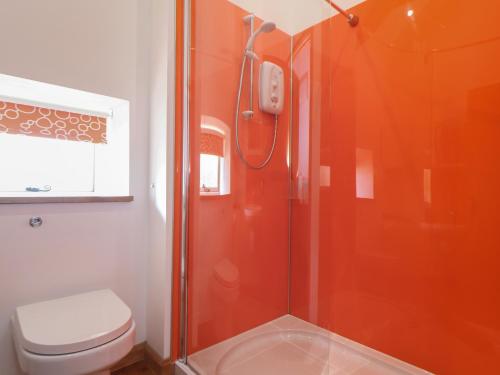 a bathroom with an orange shower with a toilet at The Piggery in Penzance