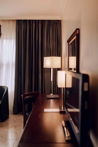 een hotelkamer met een bureau met een lamp en een televisie bij The Metropolitan Hotel Calabar in Calabar