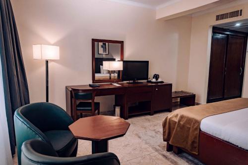 um quarto de hotel com uma secretária e uma cama em The Metropolitan Hotel Calabar em Calabar