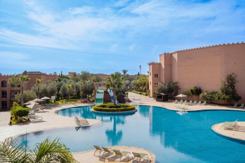Mogador Aqua Fun & Spa في مراكش: مسبح في منتجع فيه كراسي ومبنى