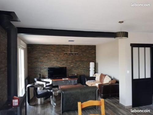 un salon avec un canapé et un mur de briques dans l'établissement L' Atelier sur les plages du débarquement, à Asnelles