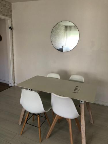 uma mesa de jantar com cadeiras brancas e um espelho em Appartement Saint-Malo Centre - Arrivée autonome em Saint Malo