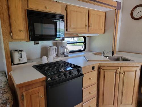 a kitchen with a stove and a sink in a caravan at Camping Beaurivage 1- Pret à camper entièrement équipée pour 6 personnes in Routhierville