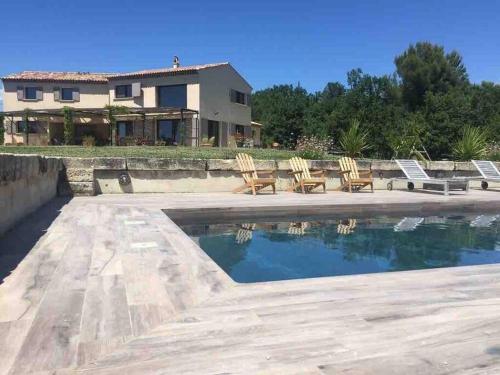 une piscine avec des chaises et une maison en arrière-plan dans l'établissement Villa avec piscine, au calme et en pleine nature!, à Pierrevert