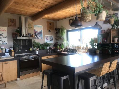 une cuisine avec un grand comptoir noir et des chaises dans l'établissement Villa avec piscine, au calme et en pleine nature!, à Pierrevert