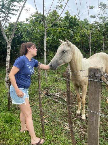 a woman is petting a white horse behind a fence at Cacahua Paradise Lodge, Río Celeste in Rio Celeste