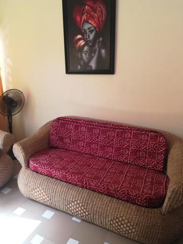 un sofá rojo en una habitación con una foto de una mujer en RésicityAB, en Abomey