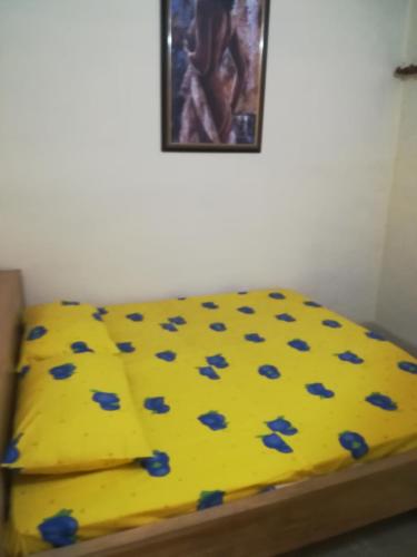 Una cama amarilla con flores azules. en RésicityAB, en Abomey