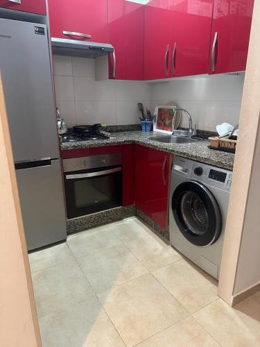 cocina con armarios rojos y lavadora en Complexe kariat cabo, en Cabo Negro