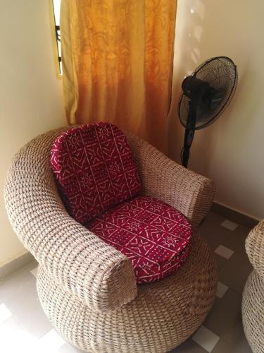 - Silla marrón con almohada roja en la habitación en RésicityAB, en Abomey