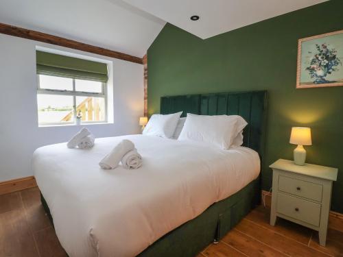 Nell's Cottage في مالتون: غرفة نوم بسرير ابيض كبير عليها مناشف