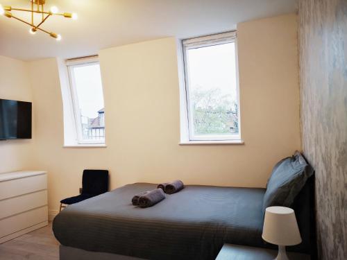 a bedroom with a bed and two windows at Stylish Studio minutes away from Wembley in London