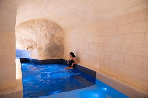 una donna seduta in una piscina d'acqua di Cenobio Hotel & SPA Matera a Matera