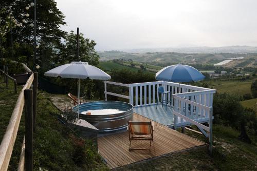 une terrasse avec une baignoire et un parasol dans l'établissement B&B L'OFFICINA DEI SOGNI, à Poggio Morello