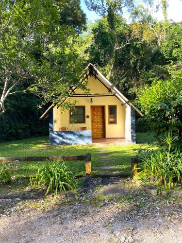 ein kleines gelbes Haus mit einem Zaun davor in der Unterkunft Pedra Grande Adventure Park in Atibaia