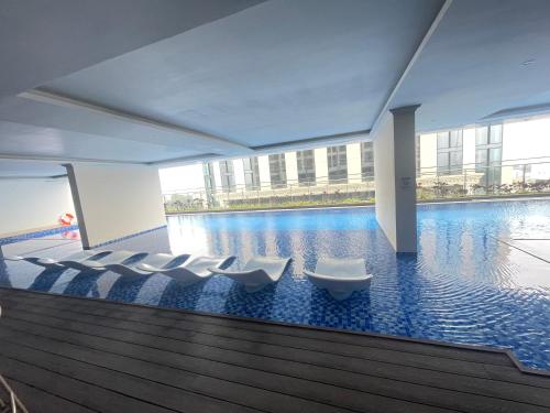 una piscina con sedie bianche in un grande edificio di Dino Home Hilton Luxury a Hai Phong