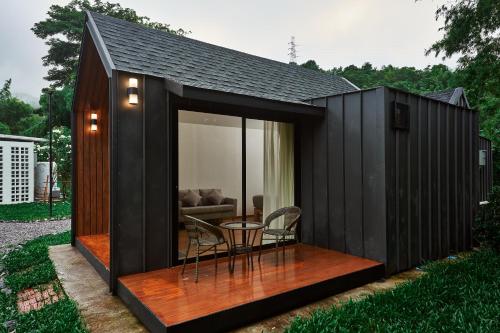 a black shed with a table and chairs in it at Baan Rai Santisuk in Ban Sok Dua