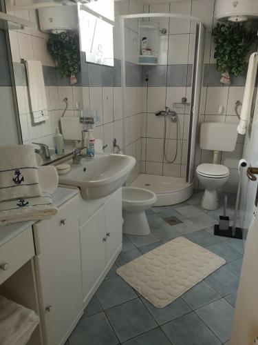 ein Badezimmer mit zwei Waschbecken, Dusche und Toilette in der Unterkunft Kuća za odmor Timón in Barbat na Rabu