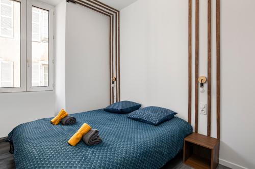 a bedroom with a blue bed with yellow pillows at Nationale 101 CahorsCityStay in Cahors