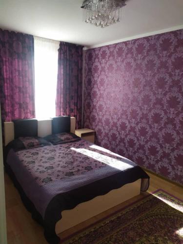 a bedroom with a large bed with purple wallpaper at Нур пансионат in Bosteri
